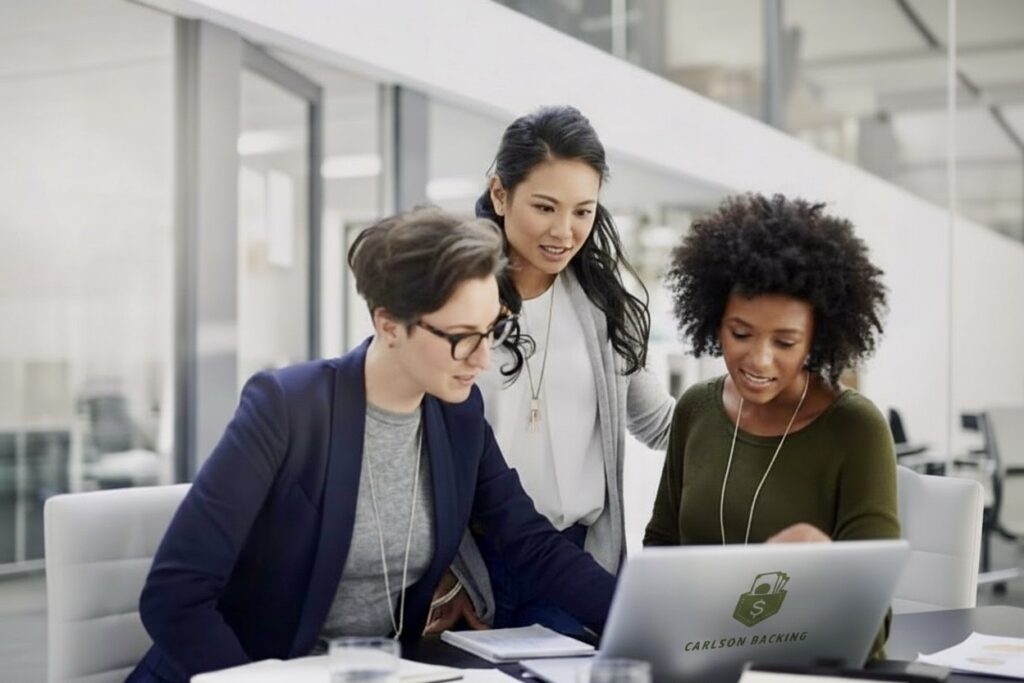 Three people collaborating around a laptop in a modern office